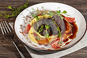 Mashed potatoes with beef in sweet and sour sauce, decorated with tomatoes and microgreens.
