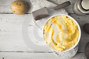 Mashed potatoes in the bowl on the white wooden table with bottle of milk top view