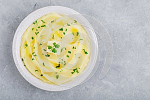 Mashed Potatoes with butter and fresh parsley in a white bowl on gray stone concrete background