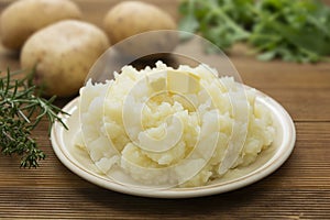 Mashed potatoes with butter and fresh white potatoes on background, wooden table. Healthy food for kids, dinner