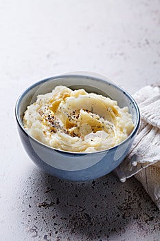 Mashed potatoes with butter and pepper in blue bowl