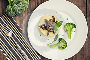 Mashed potatoes with mushrooms and boiled broccoli sauce. Wooden background. Top view. Close-up