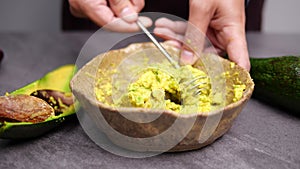 Mashing avocado in bowl. Preparing vegetarian avocado sauce. Cooking healthy food