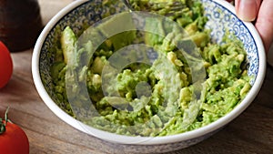 Mashing avocado with fork in a bowl