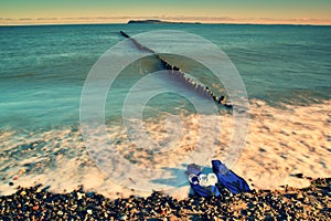 Mask with blue flippers for snorkeling ready for using on stony beach at breakwater.