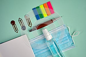 Mask, disinfectant, notepad, reading point, clips and portaminas on green background photo