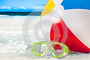 Mask goggles and color ball on a sand on beach background