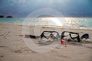 Mask and snorkel lying on sandy beach. Bokeh background.