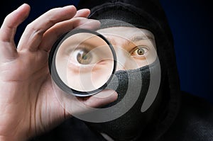 Masked anonymous hacker or spy is spying and doing espionage