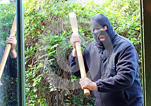 Masked burglar or robber attacking home.