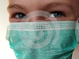 Masked child. The face of a 7-year-old boy in a protective surgical mask close-up. Schoolboy with blond hair and blue-gray eyes