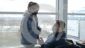 A masked couple waiting at the airport. A man and a woman at the airport during the coronavirus pandemic awaiting a