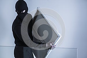 Masked criminal holding stolen picture