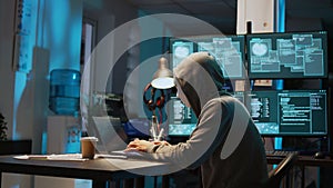 Masked data thief hacking computer network at night,