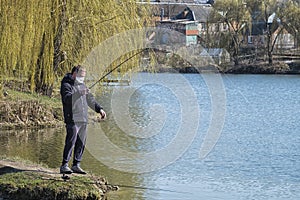 Masked fisherman catches fish following quarantine rules COVID-19