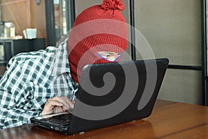 Masked hacker wearing a balaclava stealing important information data against laptop. Computer criminal concept.