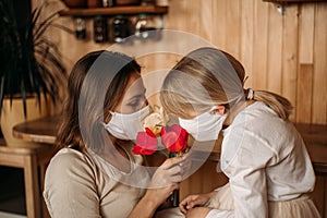 Masked happy and healthy mom and daughter in quarantine. Self isolation. Mother`s day at home