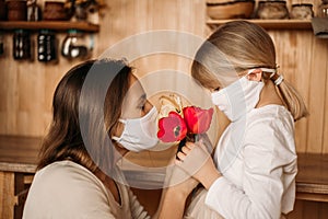 Masked happy and healthy mom and daughter in quarantine. Self isolation. Mother`s day at home