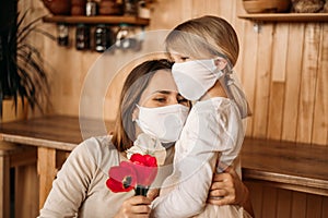 Masked happy and healthy mom and daughter in quarantine. Self isolation. Mother`s day at home