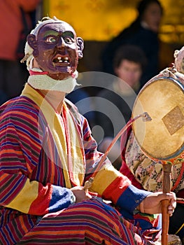 A masked man making music during a tsechus