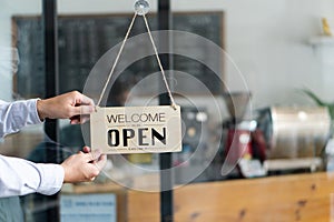 A masked middle-aged man cafe owner holds an open sign in a restaurant. small business idea