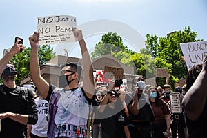 Masked protestors chant and hold signs in protest of the killing of George Floyd