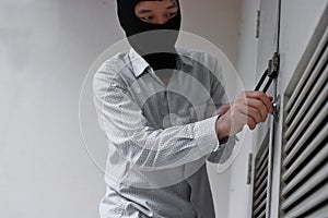 Masked robber using a lock picking tool to breaking and entering into a house. Criminal crime concept.