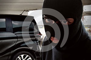 Masked thief trying to steal a car