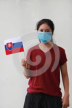 Masked woman in brown shirt and Slovakia flag in hand