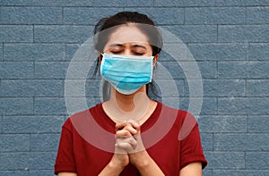 Masked woman keep the hands together and close eyes to pray for good things to happen regarding epidemics and COVID
