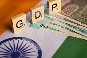 Maski,India 13,April 2019 : GDP or gross domestic product in wooden block letters on Indina flag with Indian Currency