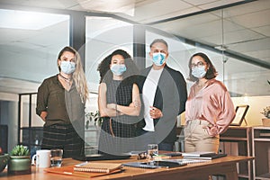 Masks on, lets accomplish business goals. a diverse group of businesspeople standing together in the office and wearing