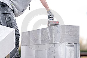 the mason applies glue to the concrete forms. construction of a wall of concrete bricks