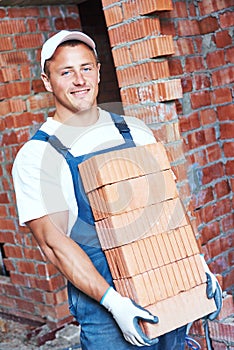 Mason bricklayer carrying red bricks