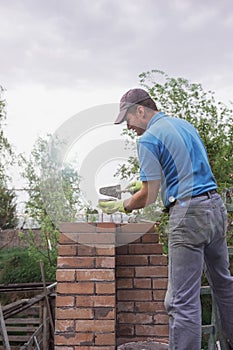 Mason building wall with bricks