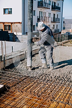 Mason building and worker using a automatic cement pump and levelling a first layer of fresh concrete