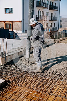 Mason building and worker using a automatic cement pump and levelling a layer of fresh concrete