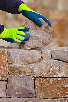 Mason hands working on masonry stone wall