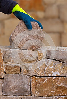 Mason hands working on masonry stone wall