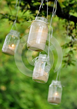 Mason jar candles hanging from a tree