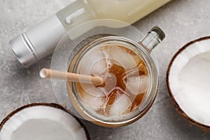 Mason jar of delicious iced coffee with coconut syrup on light grey table, flat lay