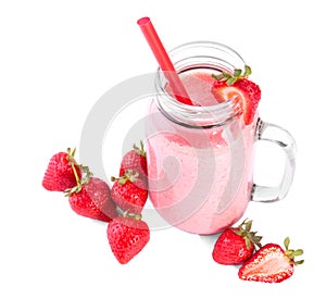 A mason jar full of organic shake. A bubbled pink milkshake on a white background. A sweet smoothie and raw strawberries.