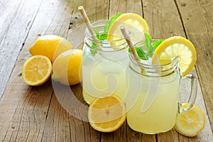 Mason jar glasses of homemade lemonade on rustic wood