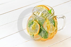 Mason jar of homemade lemonade with mint and ice on a rustic white wooden background