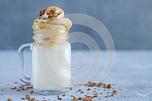 Mason jar of ice milky coffee. Refreshing summer drink on stone table copy space