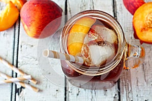 Mason jar of peach iced tea on wood, downward view