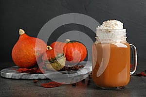 Mason jar with tasty pumpkin spice latte on table