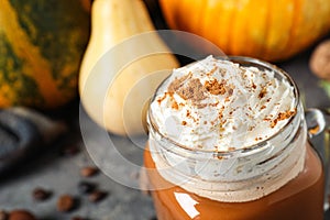 Mason jar with tasty pumpkin spice latte on table, closeup