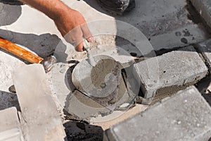 Mason lays out brickwork from gray bricks. Hands of builder with trowel close-up. Man works at construction site.