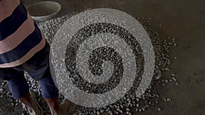 Mason worker putting down the crushed stones in a circular form to mix it with cement later on